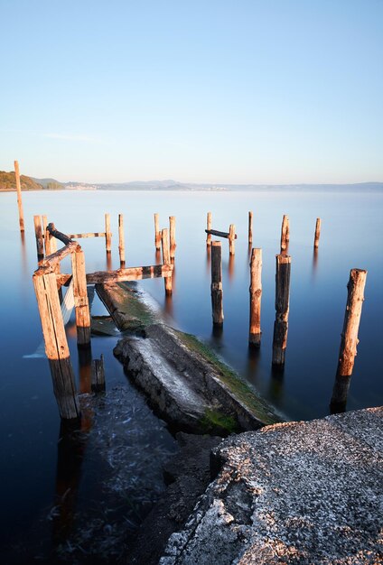 Zdjęcie długa ekspozycja jeziora bolsena z wodą i starym molo z słupami