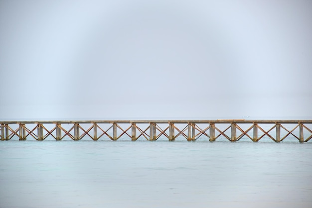 Długi poziomy most na molo na tle błękitnego nieba i wody