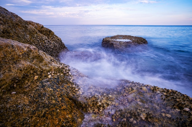 Długi ujawnienie wizerunek Dramatyczny nieba seascape z skałą w zmierzch scenerii tle