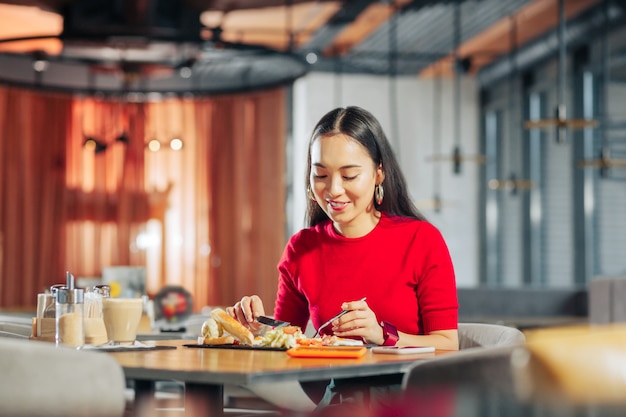 Długie Ciemne Włosy Atrakcyjna Stylowa Młoda Kobieta Z Długimi Ciemnymi Włosami Jedząca Lunch W Restauracji