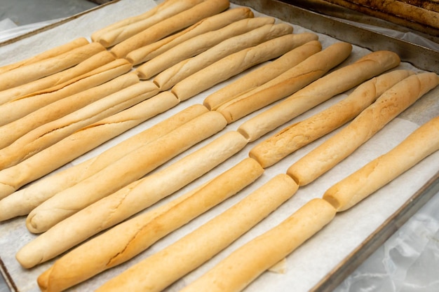 Zdjęcie długie, gorące bułeczki pszenne schładzają się po upieczeniu na metalowej blasze. świeży chleb na blasze