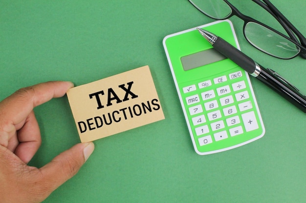 długopis, kalkulator, okulary i papier ze słowem odliczenia podatkowe. koncepcja odliczenia podatku.