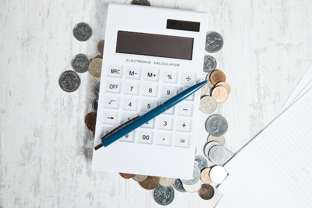 Długopis na kalkulatorze z monetami na biurku