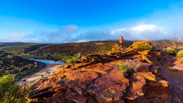 długowłosa dziewczyna spaceruje po grani po czerwonych skałach parku narodowego kalbarri w zachodniej australii