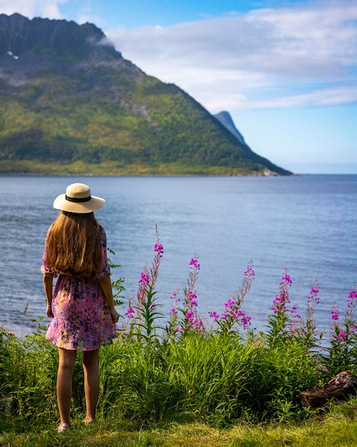 długowłosa dziewczyna w kolorowej sukience cieszy się słoneczną pogodą na wyspie senja w norwegii