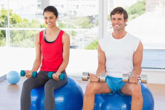 Dobiera się podnośnych dumbbells podczas gdy siedzący na sprawności fizycznych piłkach w gym