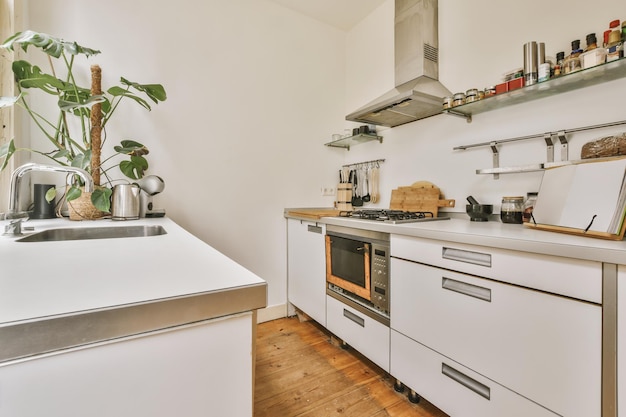 Dobrze zorganizowane wnętrze małej domowej kuchni ze zlewem przeciwko jasnym meblom z kuchenką i piekarnikiem w mieszkaniu miejskim