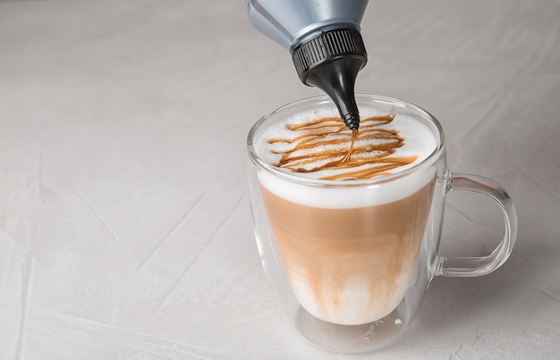 Dodawanie polewy karmelowej do latte macchiato na stole dla tekstu