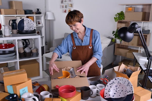 Dojrzała Azjatycka przedsiębiorczyni, właścicielka firmy pakującej produkty ceramiczne w opakowania do wysyłki i wysyłki. Biznes sprzedaży online działa w koncepcji domu