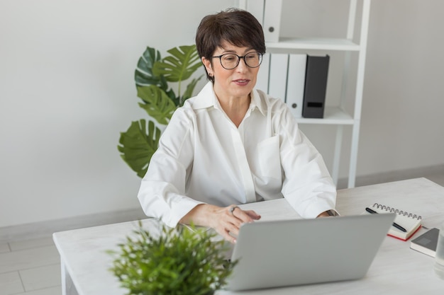 Dojrzała kobieta biznesu mówi o raporcie sprzedaży podczas wideokonferencji Kobieta korzystająca z laptopa podczas spotkania online w rozmowie wideo Praca w biurze i rozmowa wideo oraz telepraca