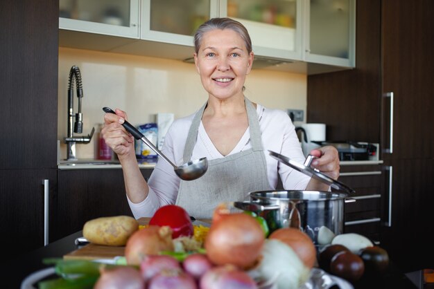 Dojrzała kobieta przygotowuje jedzenie w kuchni