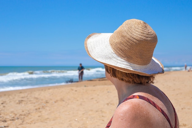 Dojrzała kobieta w kapeluszu na piaszczystym brzegu patrzy na morze od strony morza Reszta emerytów w Rosji