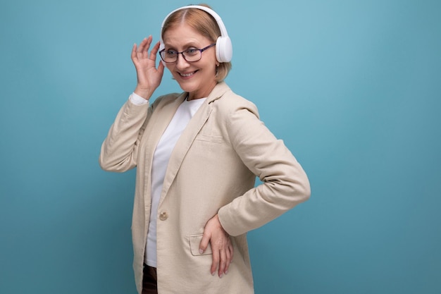 Dojrzała kobieta w kurtce słuchająca muzyki w słuchawkach bezprzewodowych
