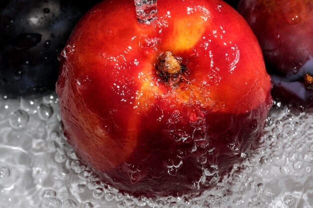 Dojrzała słodka nektarynka jest myta pod strumieniem czystej wody makrofotografii z bliska