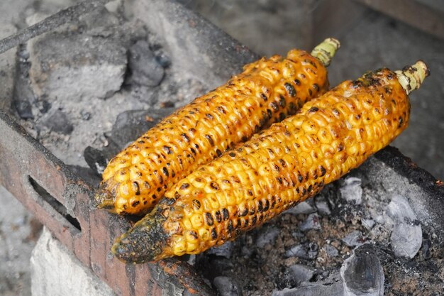 Zdjęcie dojrzała żółta kukurydza grillowana na grillu z płonącym węglem drzewnym gotowa do podania