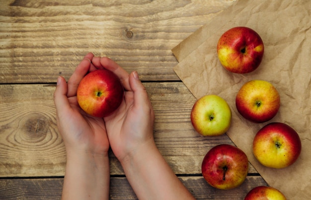 Dojrzałe, soczyste jabłko jest trzymane przez kobiece ręce na drewnianym tle. Wegetarianizm. Zdrowe odżywianie i dieta.