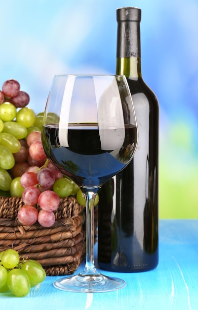 Dojrzałe zielone i fioletowe winogrona w koszyku z winem na drewnianym stole na naturalnym tle