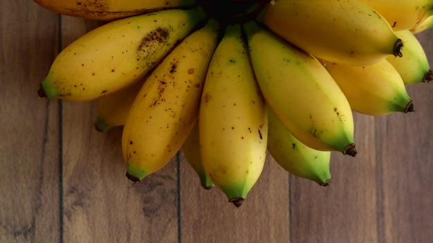 dojrzałe żółte banany skupione na drewnianym tle. Małe banany owocowe.
