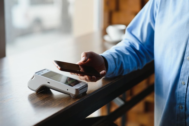 Dojrzały biznesmen płaci zbliżeniową kartą kredytową z technologią NFC