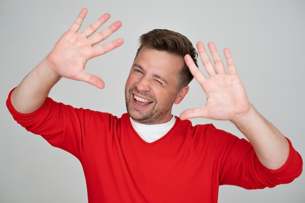 Dojrzały kaukaski mężczyzna pokazuje numer dziesięć z palcami na dłoni, uśmiechając się pewnie