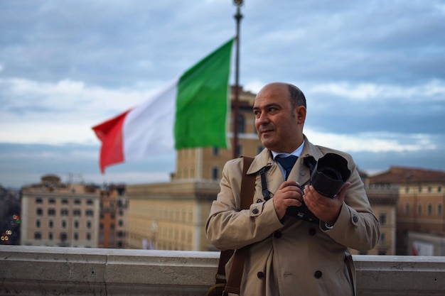 Dojrzały mężczyzna fotografuje, stojąc w mieście na tle nieba.