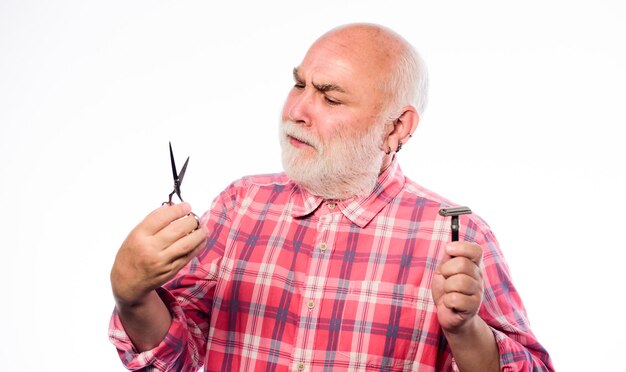 Dojrzały mężczyzna fryzjer trzyma nożyczki i ostrze do golenia na białym tle Przycinanie brody i wąsów Usługi pielęgnacji Przycinanie zarostu na twarzy Przycinanie lub golenie Wybierz idealną długość i kształt brody