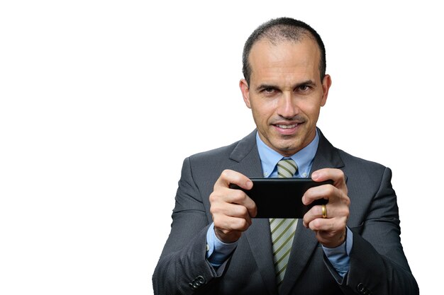 Dojrzały mężczyzna w garniturze i krawacie, uśmiechając się i trzymając smarthphone poziomo.