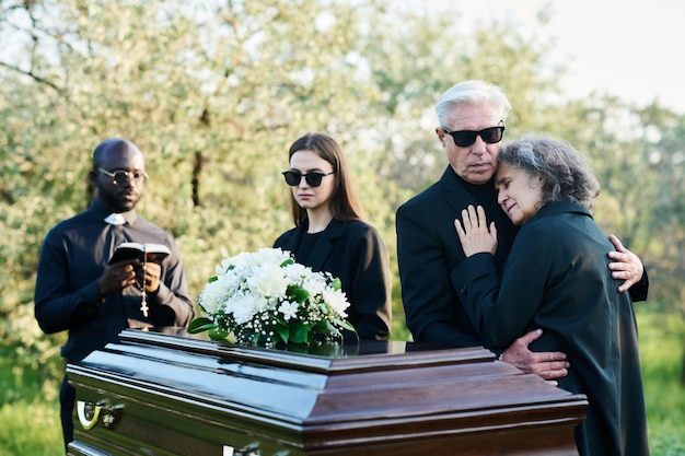 Zdjęcie dojrzały mężczyzna wspierający niepocieszoną żonę podczas żałoby na pogrzebie