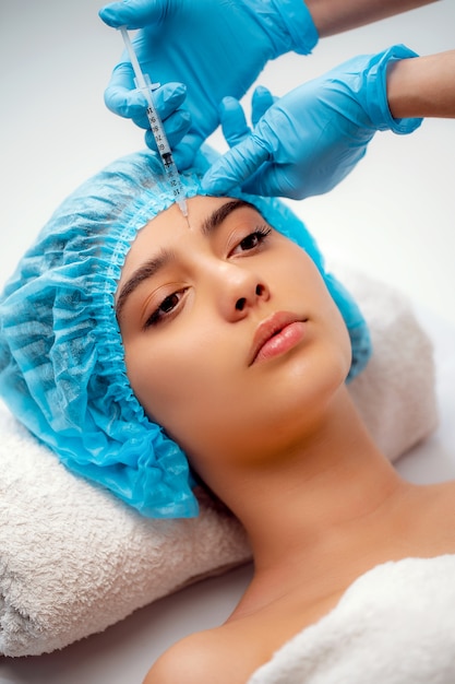 Doktor kosmetolog wykonuje zabieg odmładzania zastrzyków twarzy w celu napinania i wygładzania zmarszczek na skórze twarzy kobiety w salonie piękności. Kosmetyki do pielęgnacji skóry