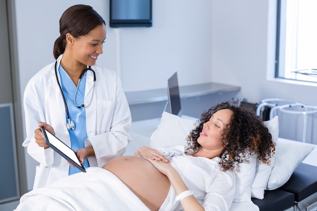 Doktorski pokazuje ultradźwięk skanuje kobieta w ciąży na cyfrowej pastylce