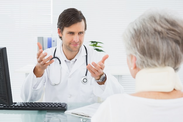 Doktorski słuchanie starszy pacjent przy medycznym biurem