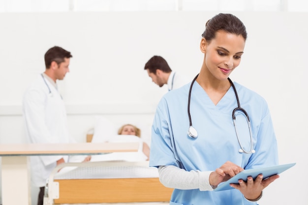 Doktorski używa cyfrowy pastylka z kolegami i pacjentem behind