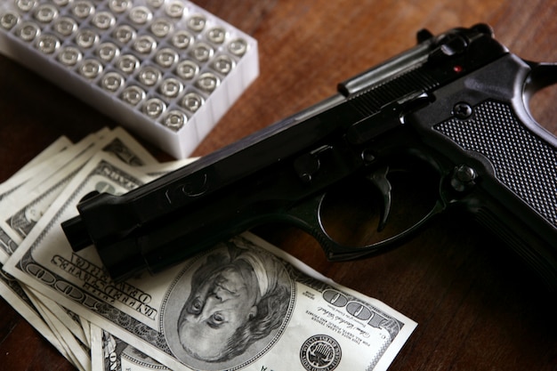 Dolarowe notatki i pistolet, czarny pistolet