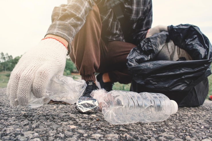 Zdjęcie dolna część człowieka zbierająca śmieci na drodze