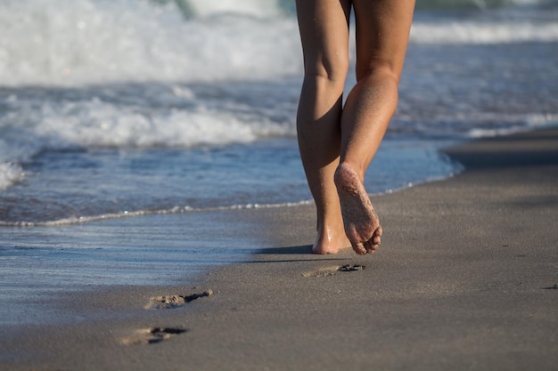 Dolna część kobiety idącej po brzegu na plaży