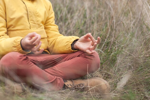 Zdjęcie dolna część osoby medytującej na polu