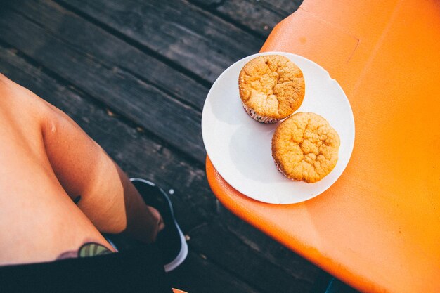 Zdjęcie dolna część osoby siedzącej z muffinami