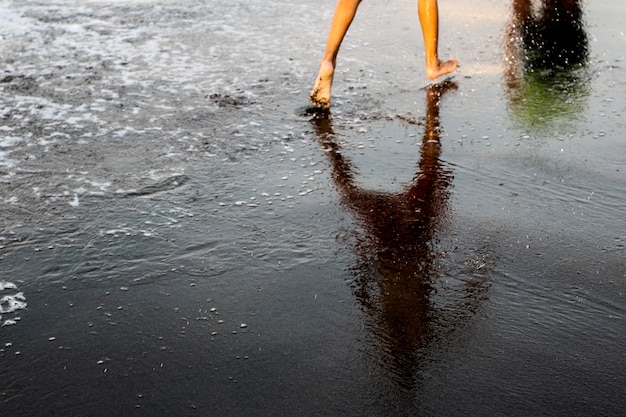 Dolna część osoby spacerującej po plaży