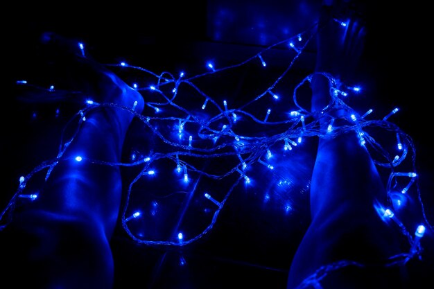 Zdjęcie dolna część osoby z oświetlonymi światłami strunowymi w ciemni w nocy