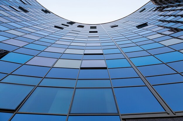 Dolny widok błękitna szkło powierzchnia buduje frontową ścianę półkole odbija niebieskie niebo