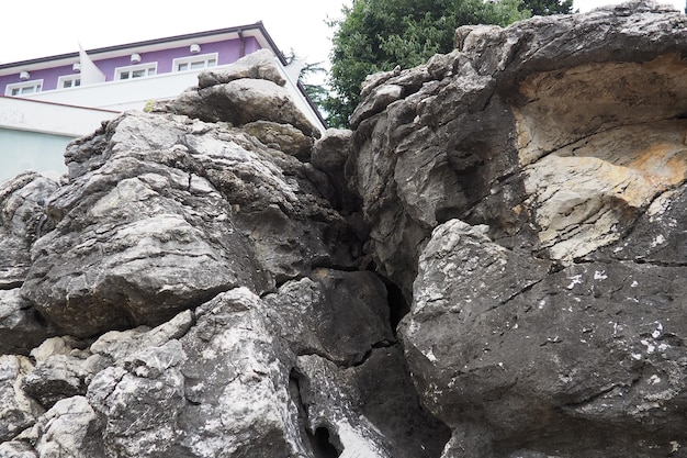 Dom hotelowy na skraju skały stwardniała lawa wulkaniczna Herceg Novi Czarnogóra Duża szczelina w skale Jaskinia Warstwy w skale Geologia i sejsmologia regionu Adriatyku Morza Śródziemnego