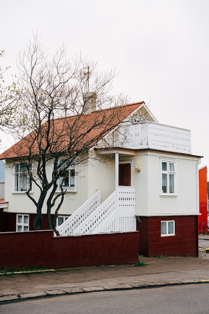 Dom jest kremowy z pomarańczowymi balustradami na schodach przed wejściem