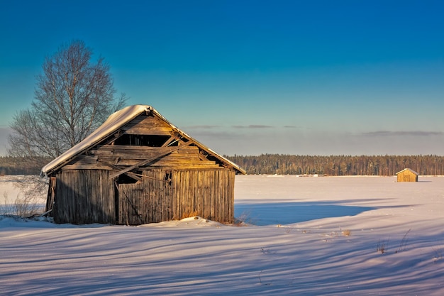 Zdjęcie dom na pokrytym śniegiem polu na tle niebieskiego nieba