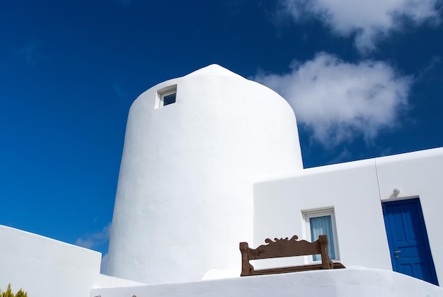 Dom w Mykonos, Grecja. Bielony budynek na słonecznym niebieskim niebie. Typowa architektura i design domu. Letnie wakacje na śródziemnomorskiej wyspie. Koncepcja wędrówki i podróży.