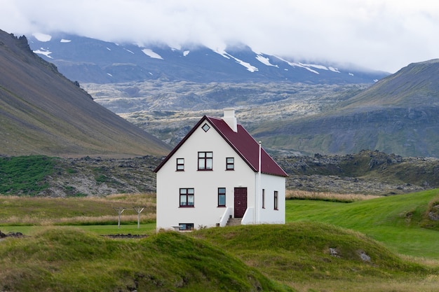 Dom wiejski na wzgórzu na Islandii z zachmurzonym niebem i ładnym widokiem