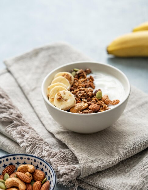 Zdjęcie domowa granola z bananem i orzechami w misce na niebieskim tle z serwetką