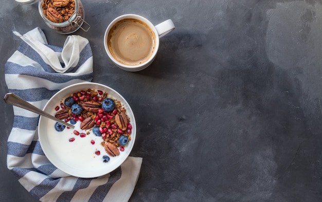 Domowa Muesli Z Granatem, Jagodami, Orzechami Pekan I Jogurtem Na Szarym Betonowym Tle.