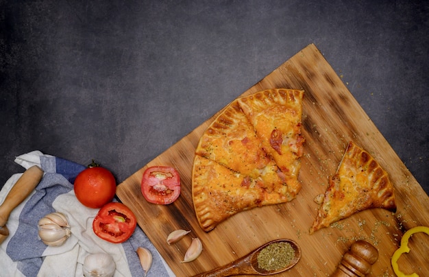 Domowa pizza hawajska. Ptyś do pizzy z serem drewniany talerz tło. Gotowanie w domu na ferie zimowe.