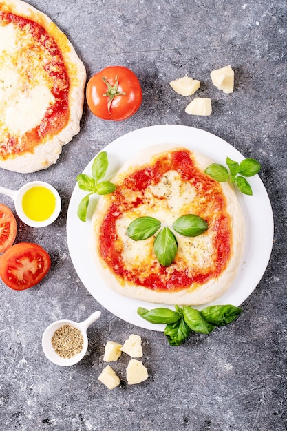 Zdjęcie domowa pizza margherita z serem mozzerala podana ze świeżą bazylią, przyprawami oregano i pomidorami na niebieskiej powierzchni. widok z góry, płaski układ.