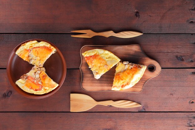 Domowa pizza na glinianej płytce i desce do cięcia Pizza i drewniane sztućce na brązowym tle